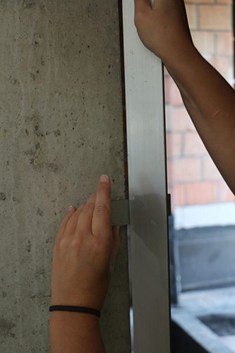 De rechtheid van de rand van een muur uit beton wordt gemeten met een lat van 2 m en een diktemaat.
