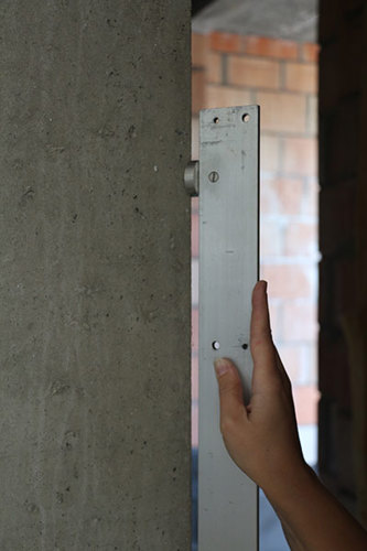 De rechtheid van de rand van een muur uit beton wordt gemeten met een lat van 2 m. Deze foto is een detailopname van hoe de controlelat van 2 m op de rand dient geplaatst te worden.