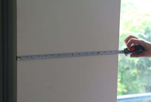 Meten van de breedte van een muurgedeelte met behulp van een rolmeter.
